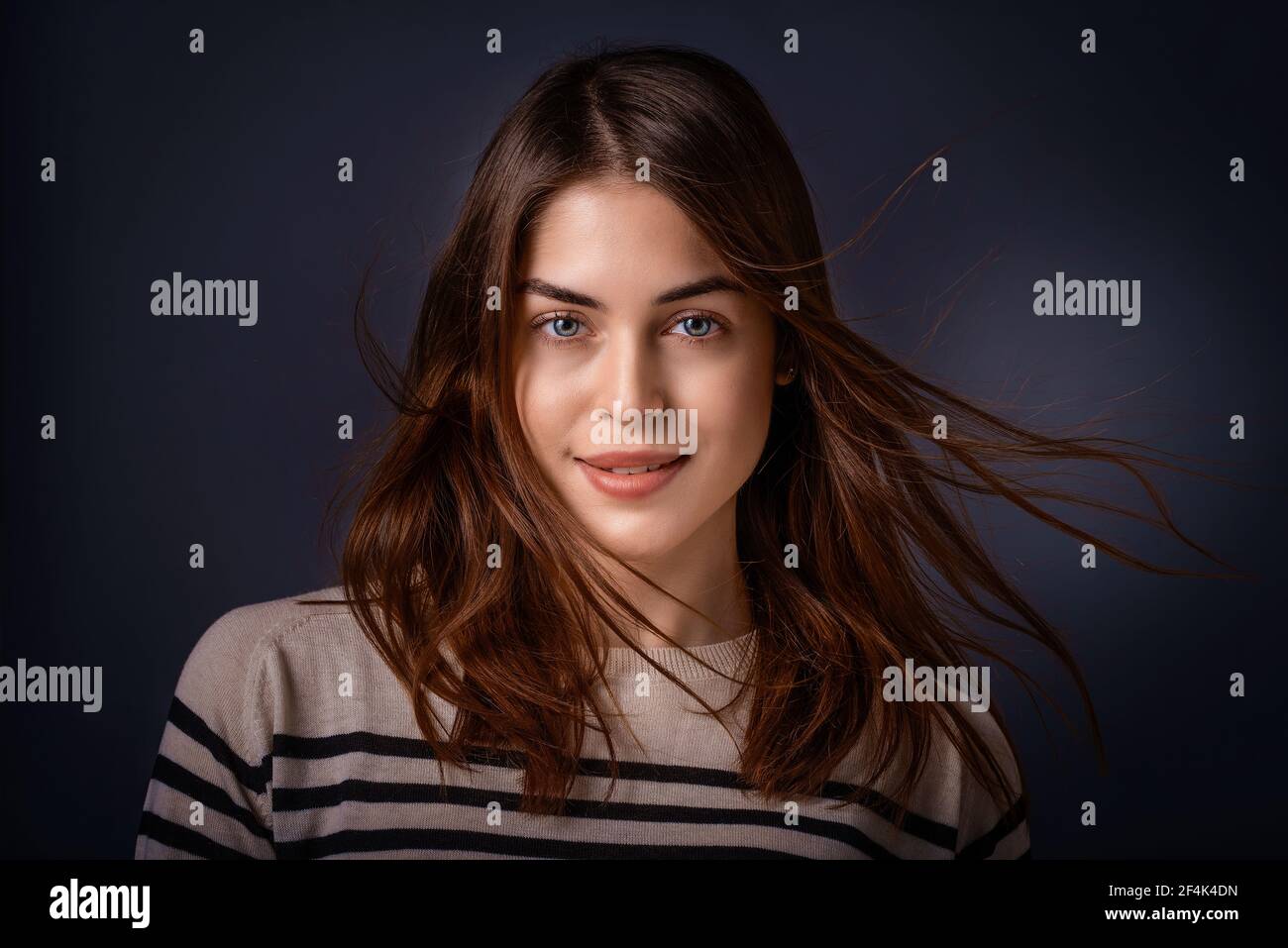 Studio portrait of beautiful young woman looking at camera and smiling ...