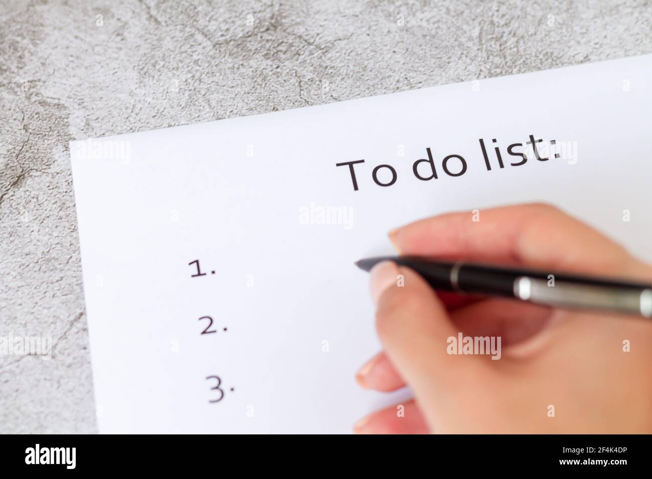 Hand writing business plan, strategy or goals. To do list on blank paper page on light gray stone background close-up Stock Photo