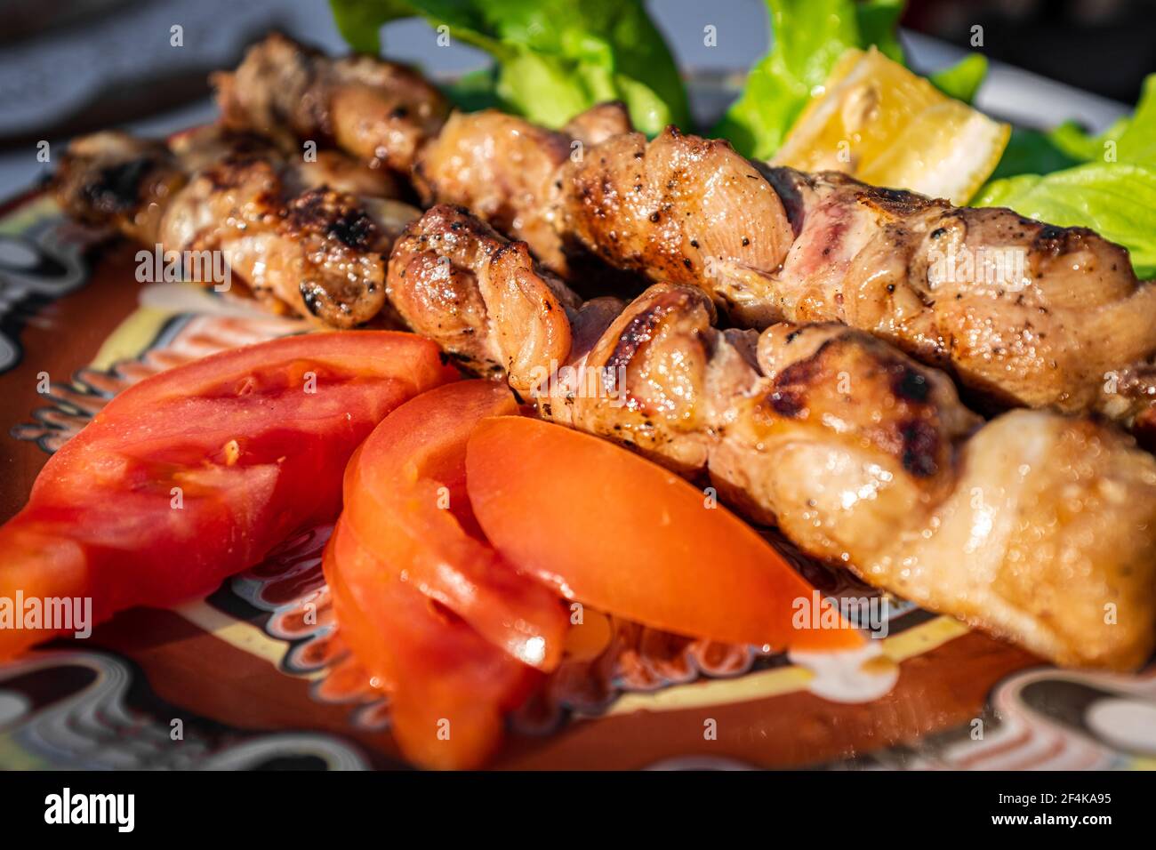 BBQ chicken skewers with tomatoes and lettuce salad. close up. BBQ grilled chicken skewers with tomatoes and lettuce salad. close up. Stock Photo