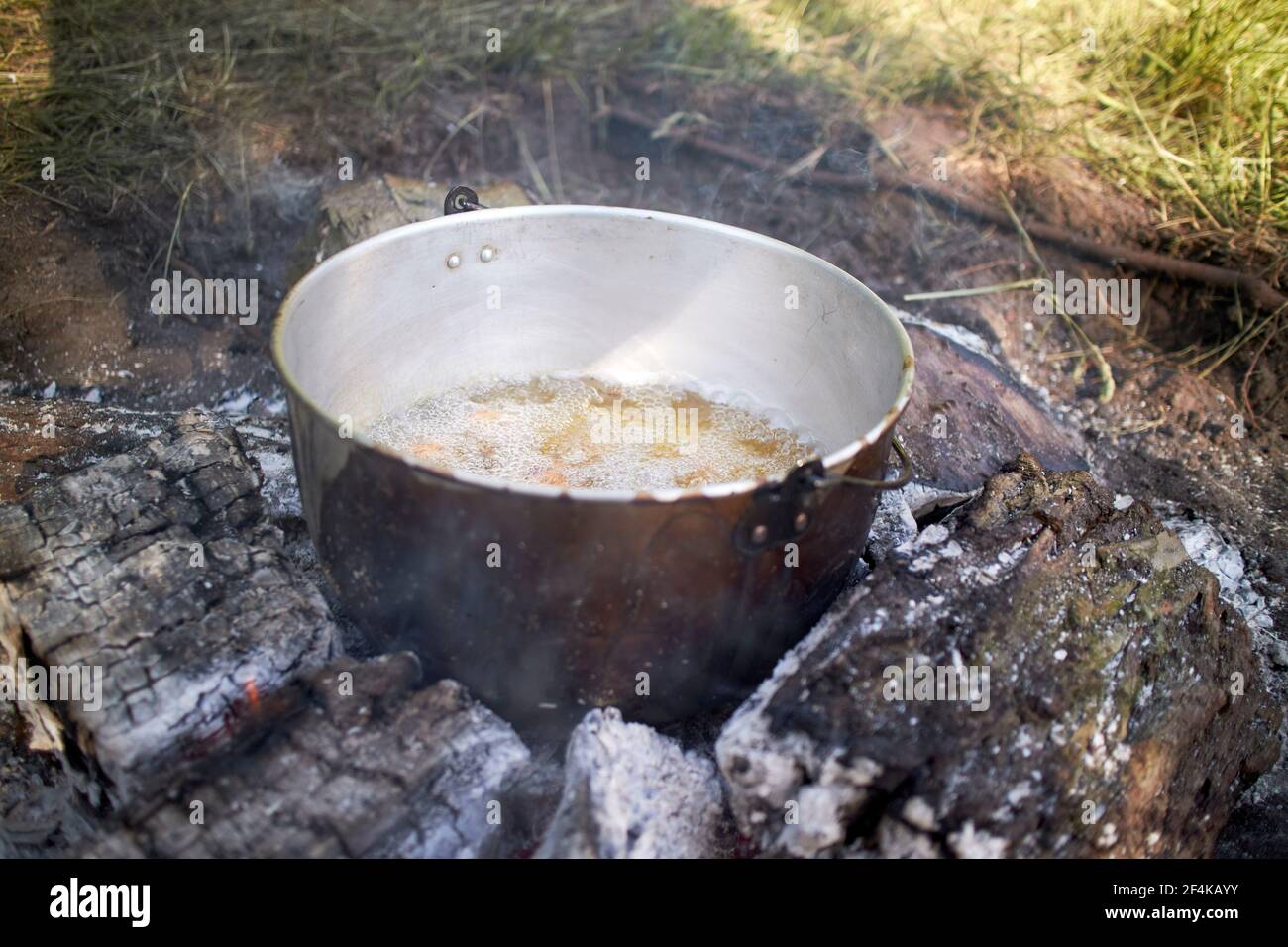 a pot cooking food outdoors on fire Stock Photo