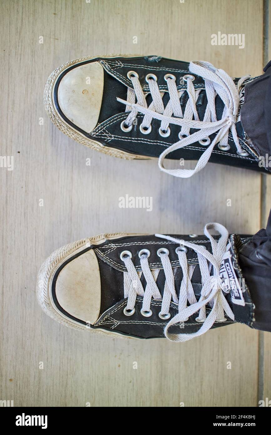 a person wearing black dirty converse shoes Stock Photo - Alamy