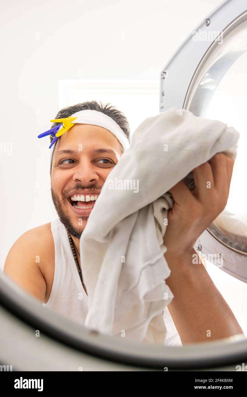 Young man with unkempt appearance prepares his clothes to be washed in the washing machine Stock Photo