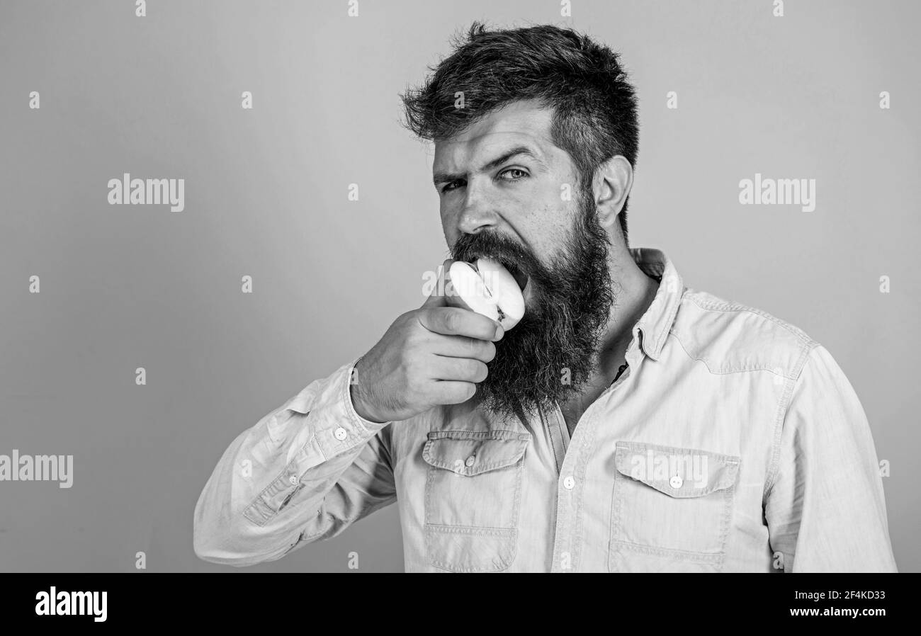 Man diet nutrition eats fruit. Healthy nutrition concept. Man handsome hipster with long beard eating apple. Hipster hungry bites juicy ripe apple. I Stock Photo
