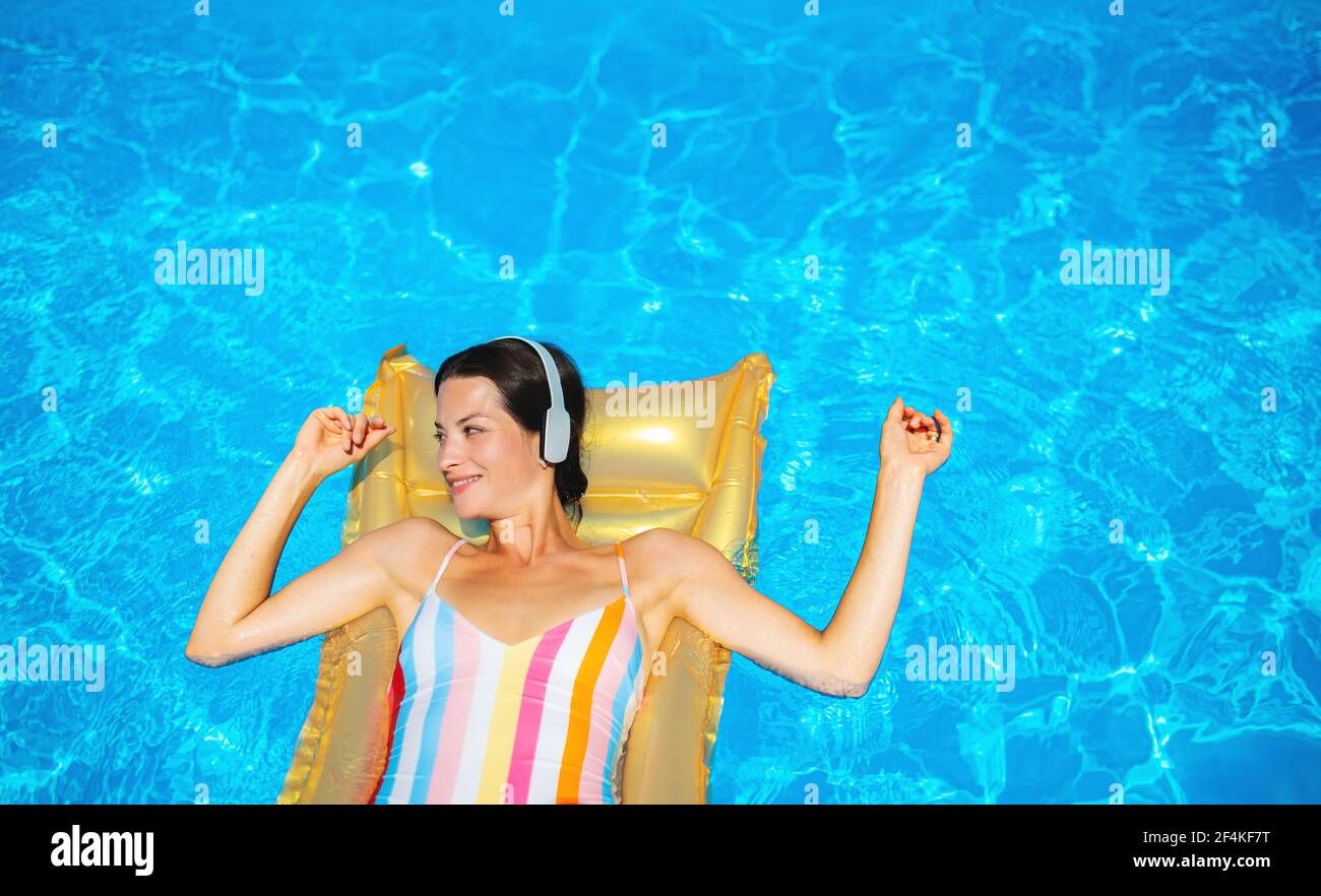 Top view of young woman in swimming pool outdoors on floating bed ...