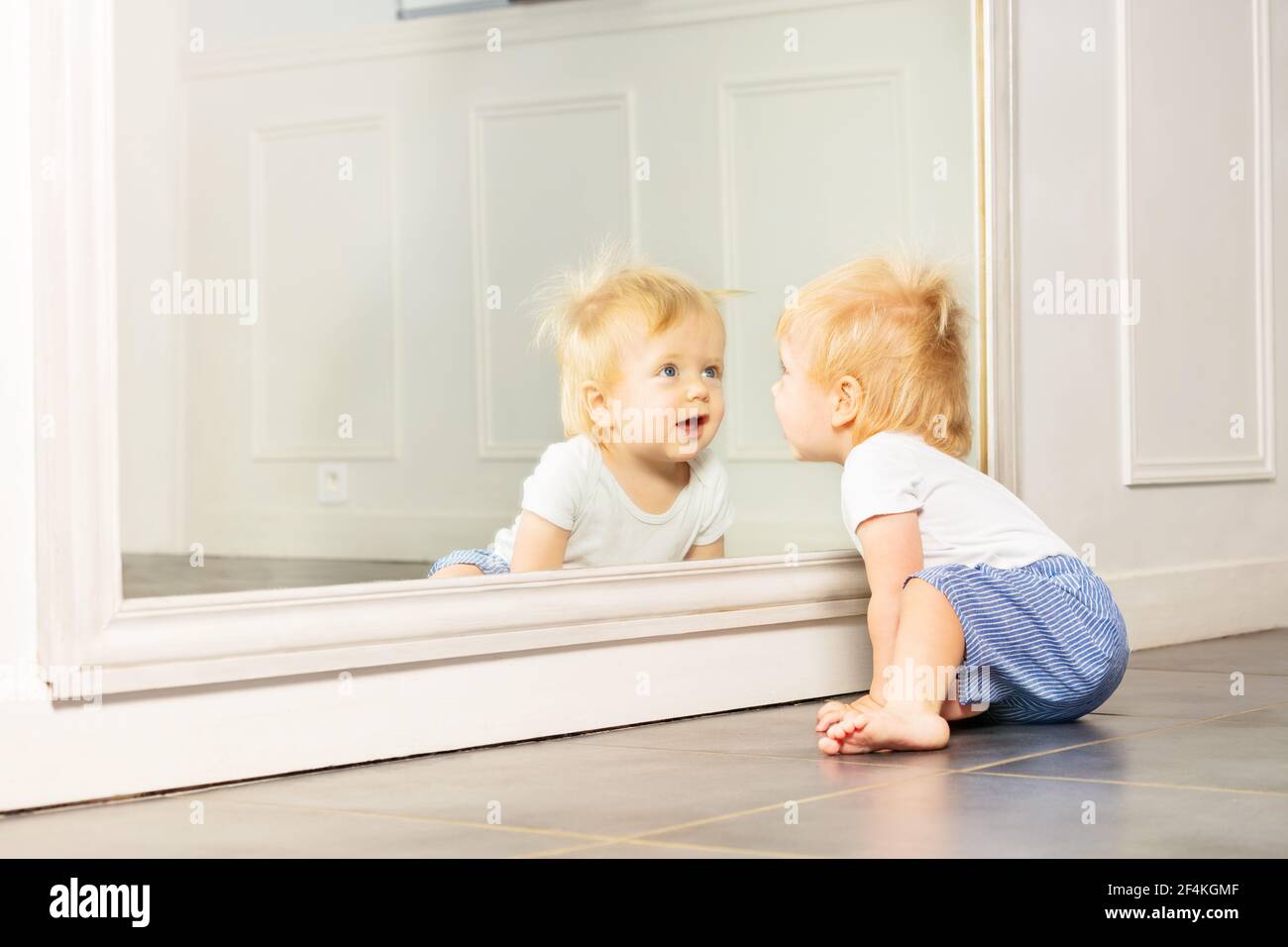 Little toddler boy play with big mirror on wall Stock Photo Alamy