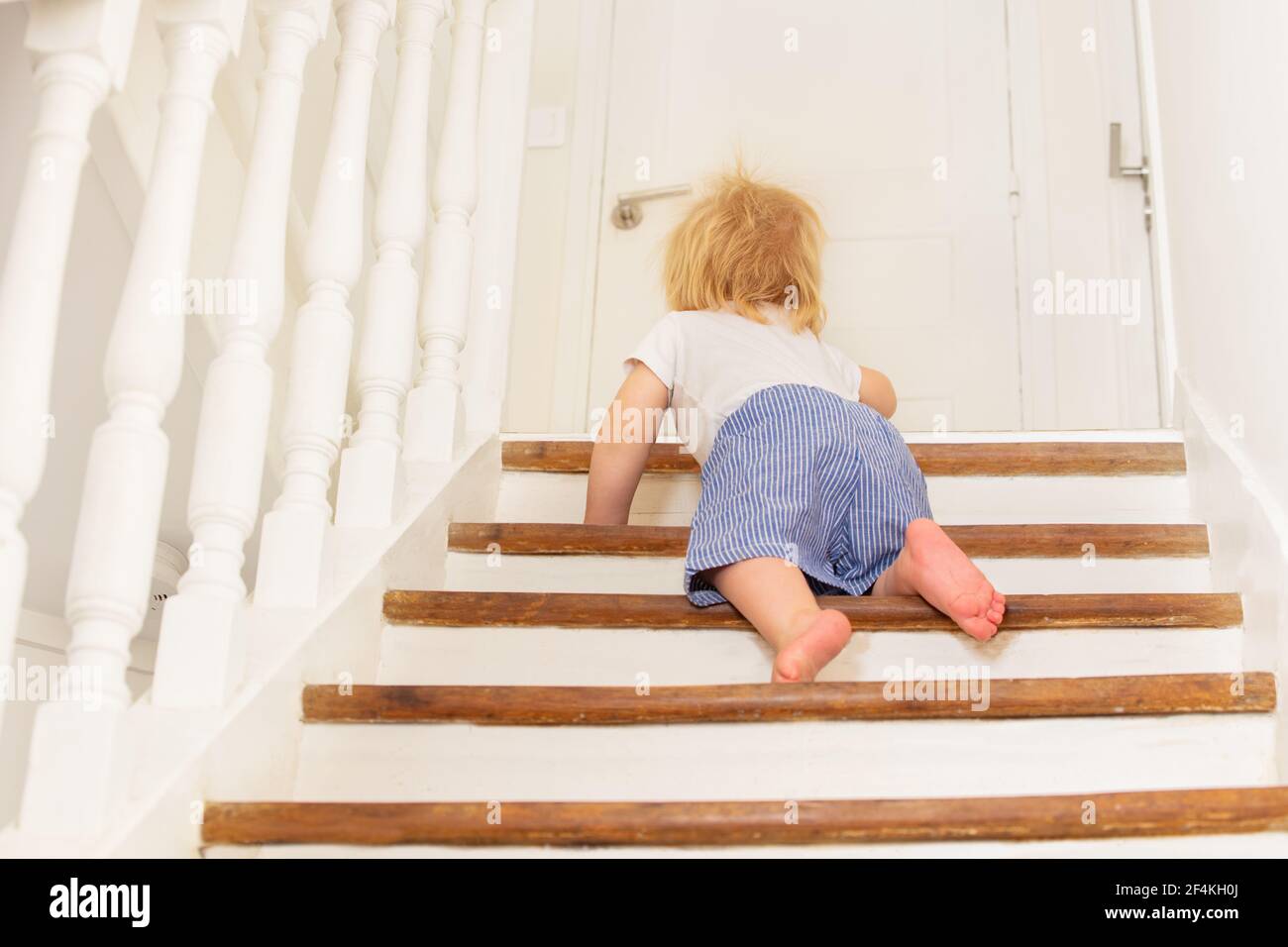 View from behind of a toddler climbing staircase Stock Photo - Alamy