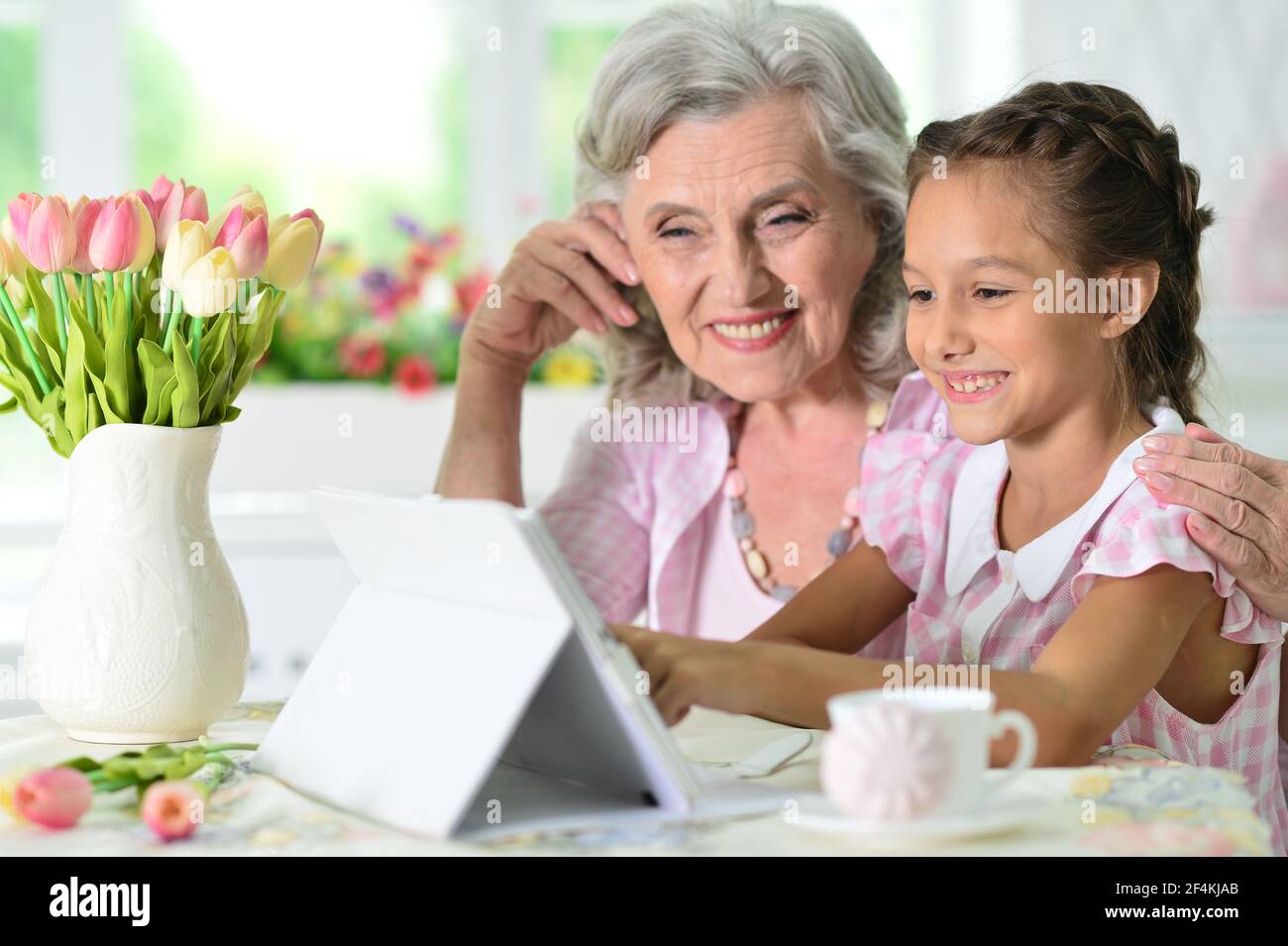 Cute little girl with her grandmother looking at tablet Stock Photo - Alamy