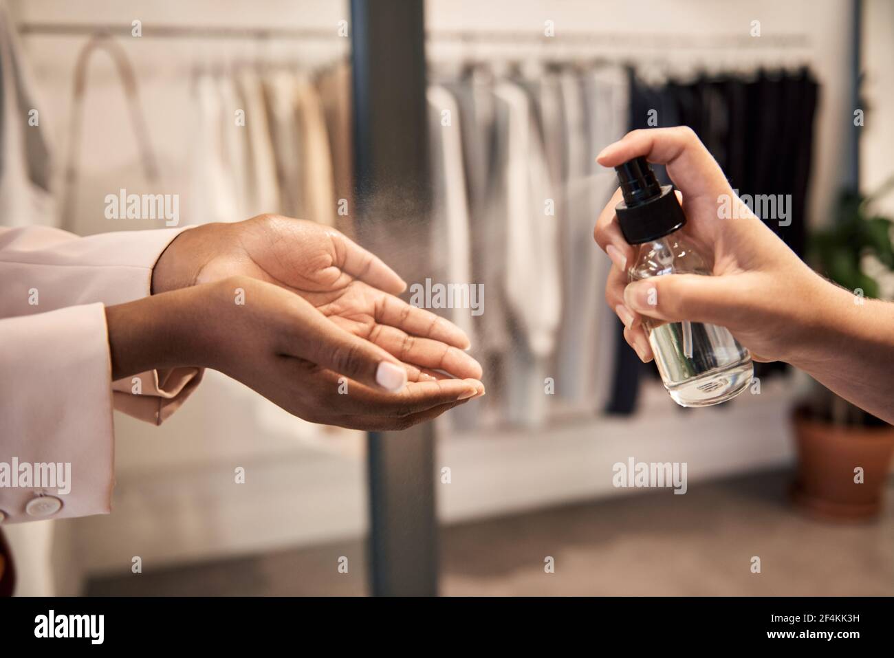 Shop assistant spraying sanitizer on a customer's hands Stock Photo