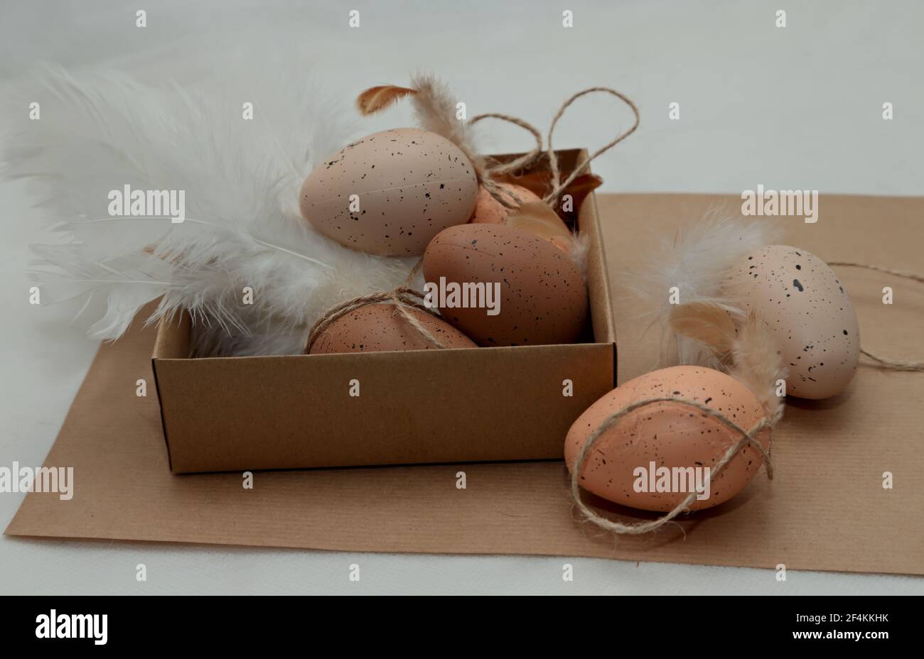 Brown easter eggs with white feathers in a cardboard box on a table Stock Photo