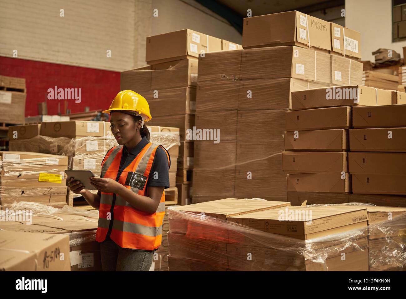 Young African female warehouse worker doing inventory using a tablet Stock Photo