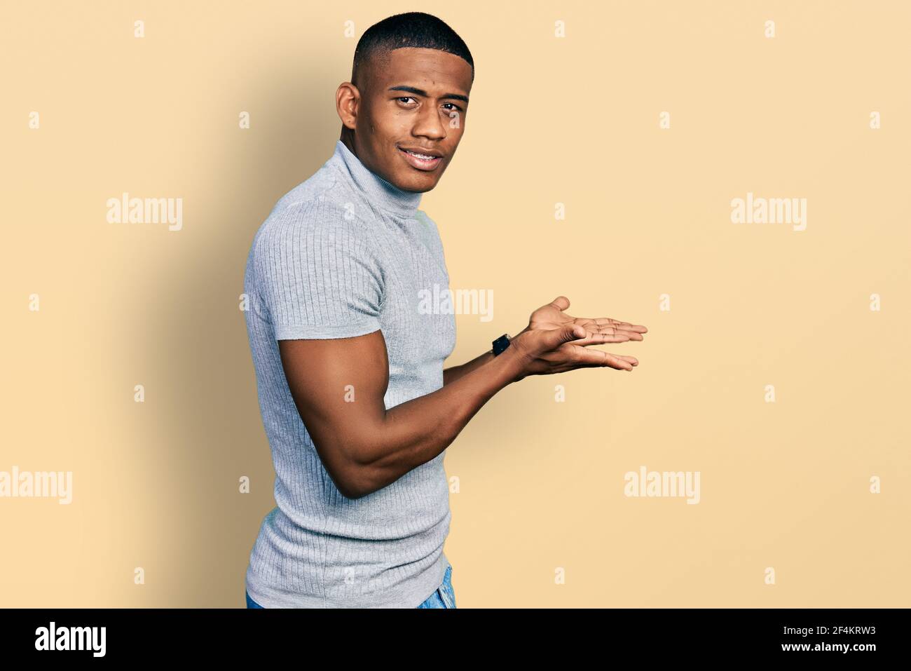 Young black man wearing casual t shirt pointing aside with hands open ...