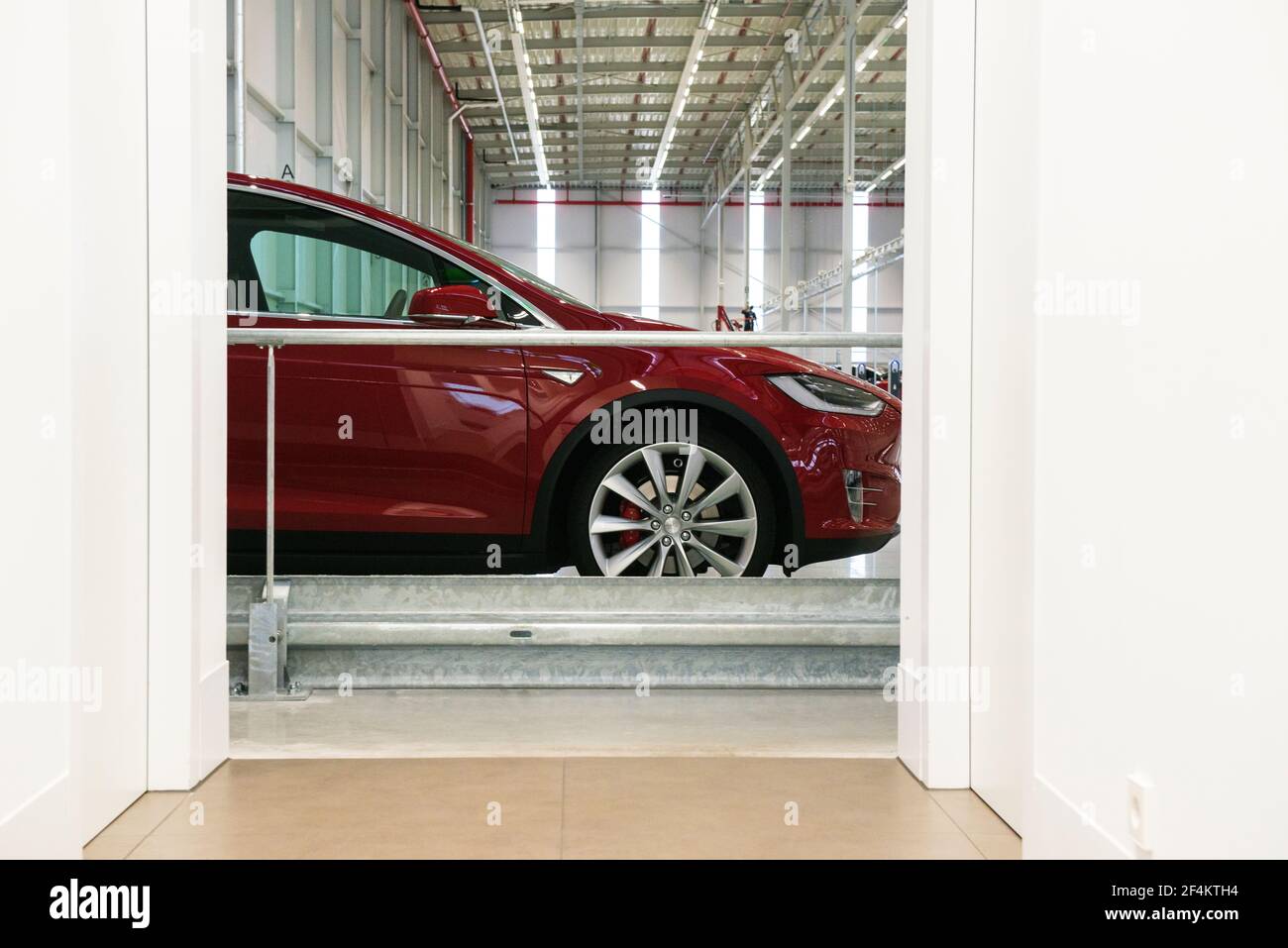 A red colored Tesla Model X parked and recharging inside the factory warehosue. Stock Photo