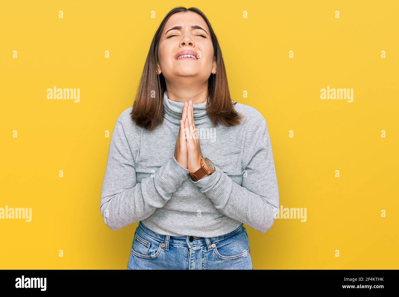 Young beautiful woman wearing casual turtleneck sweater begging and praying with hands together with hope expression on face very emotional and worrie Stock Photo