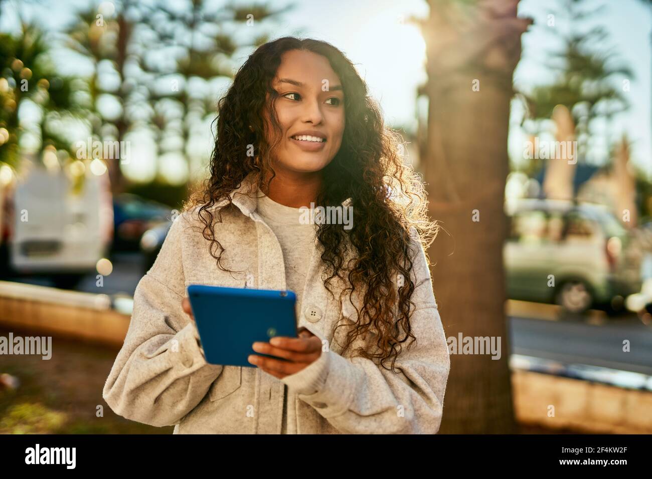 Young latin woman smiling happy using touchpad at the city Stock Photo ...