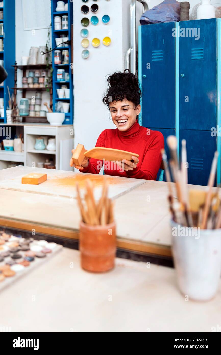 Stock photo of happy woman sanding pot in pottery class. Stock Photo