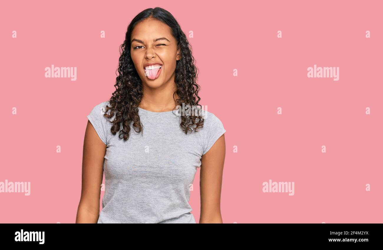 Young african american girl wearing casual clothes sticking tongue out ...