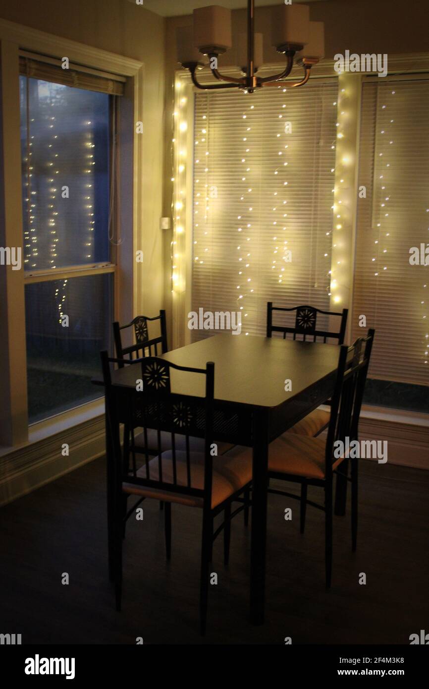 soft strung lights cascade behind a simple dinette set Stock Photo