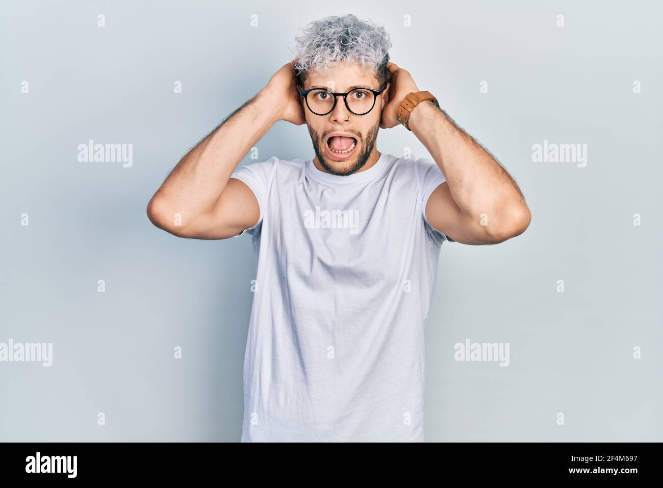 Young hispanic man with modern dyed hair wearing white t shirt and glasses  crazy and scared with hands on head, afraid and surprised of shock with ope  Stock Photo - Alamy