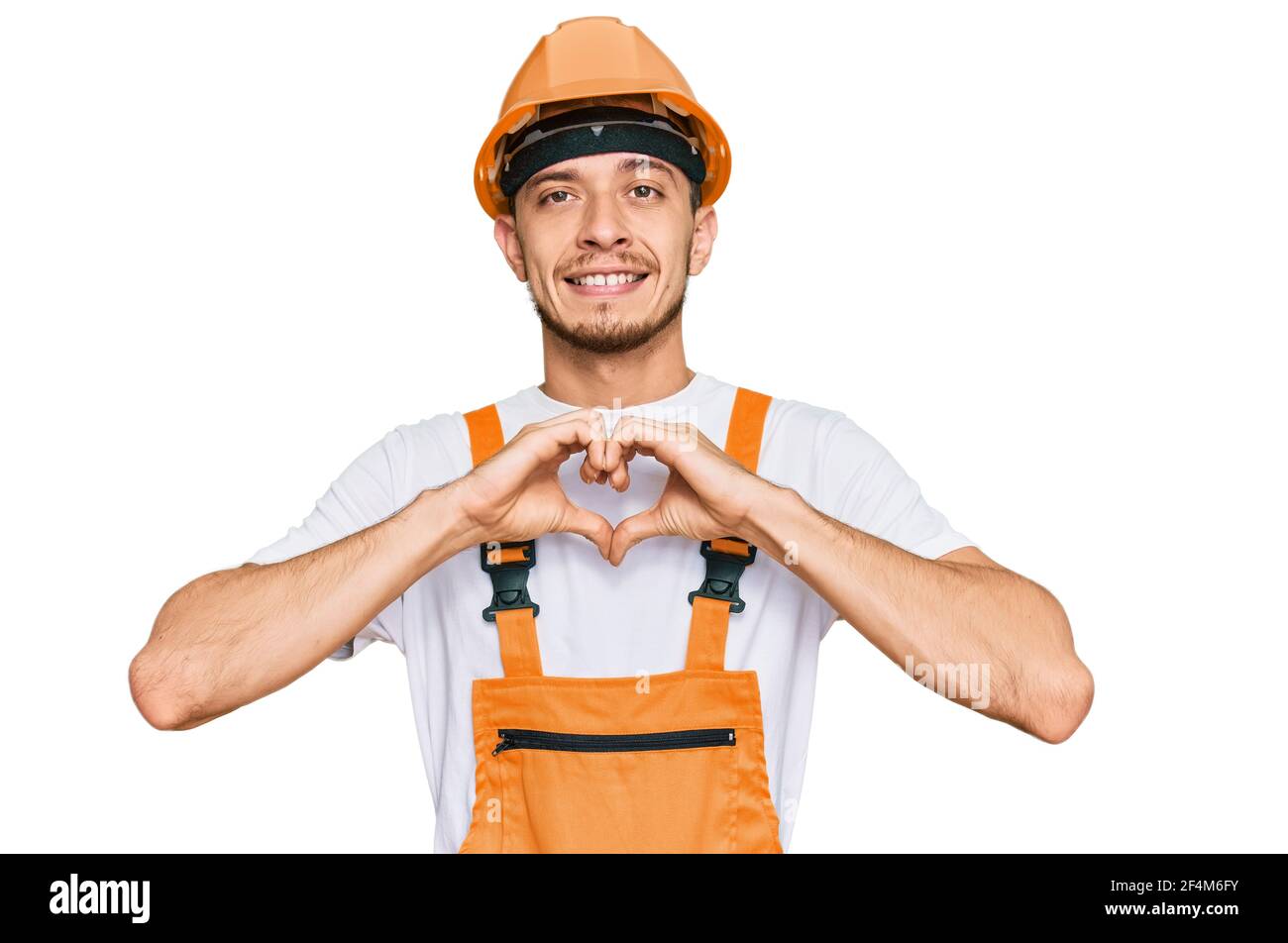 Hispanic young man wearing handyman uniform and safety hardhat smiling