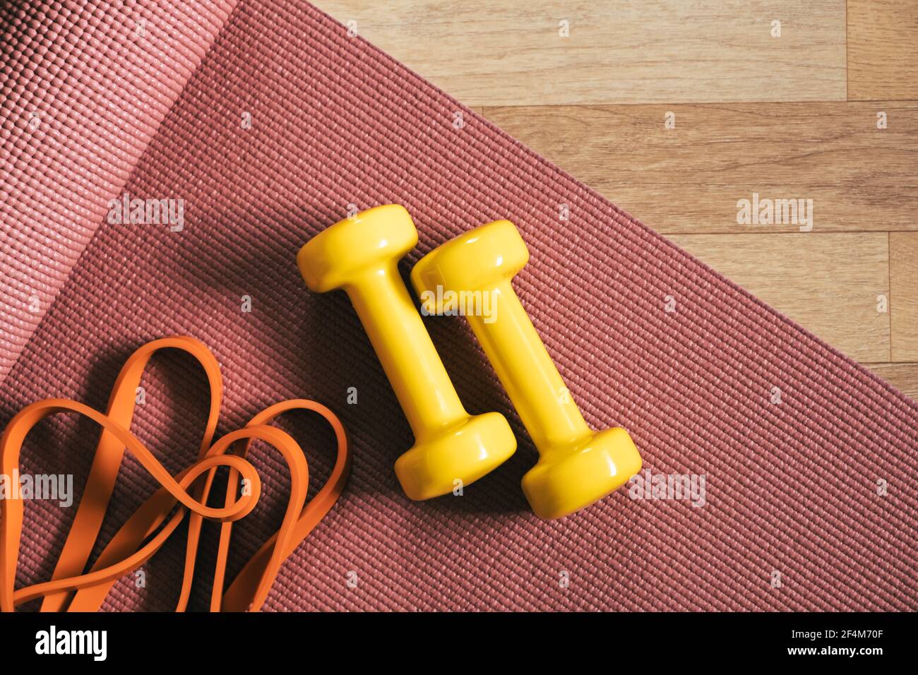 Training, being fit at home in lockdown. Yoga mat, fitness gum and barbells on the floor, top view Stock Photo