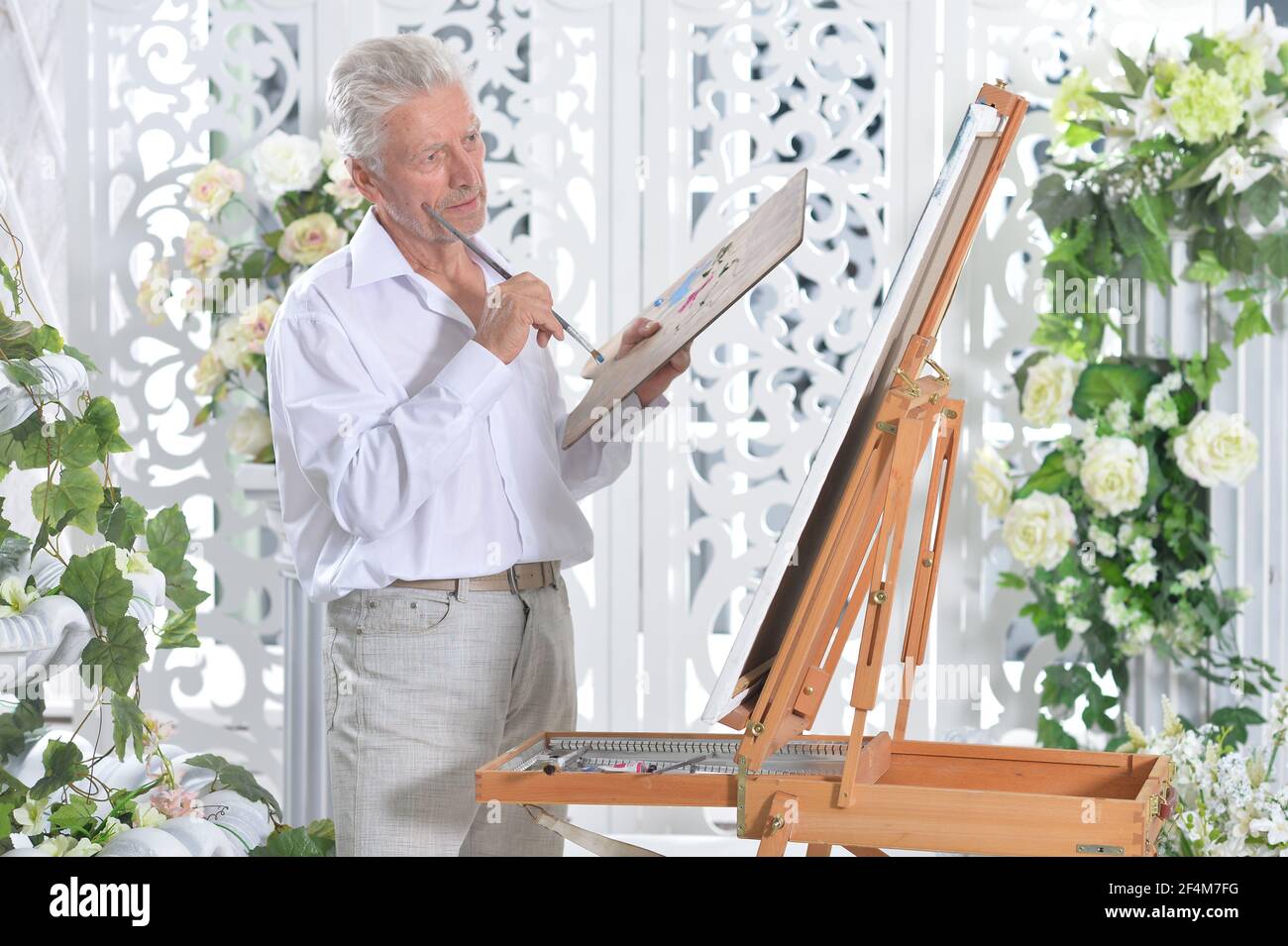 Portrait of elderly man painting with easel Stock Photo - Alamy