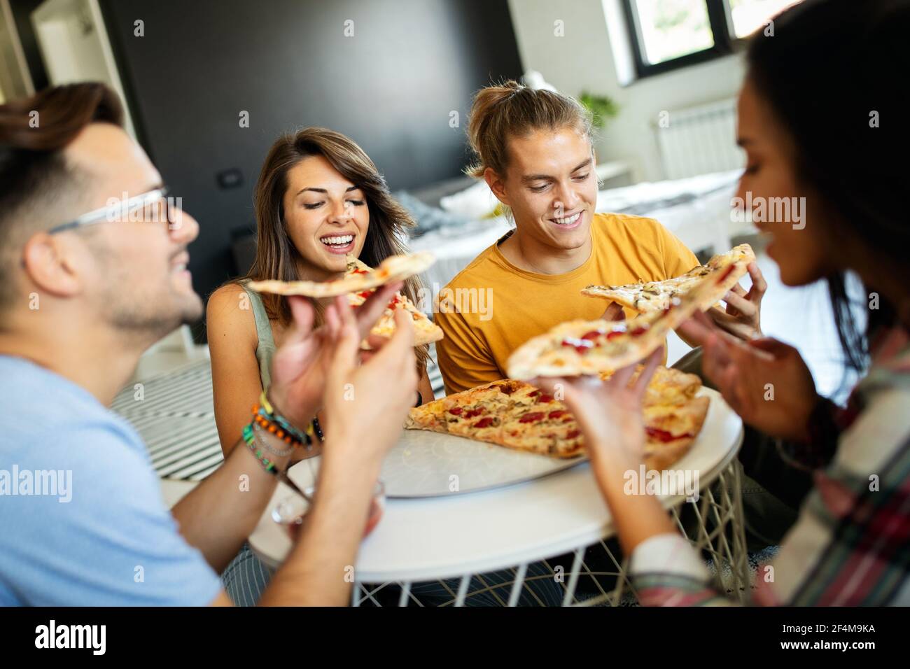 Spending time with friends. Group of cheerful young people talking and eating pizza together Stock Photo