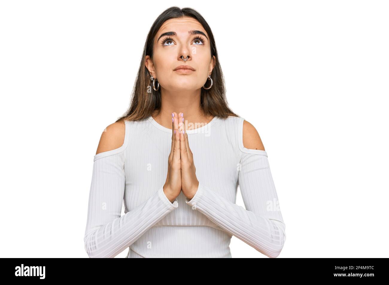 Young hispanic woman wearing casual clothes begging and praying with ...