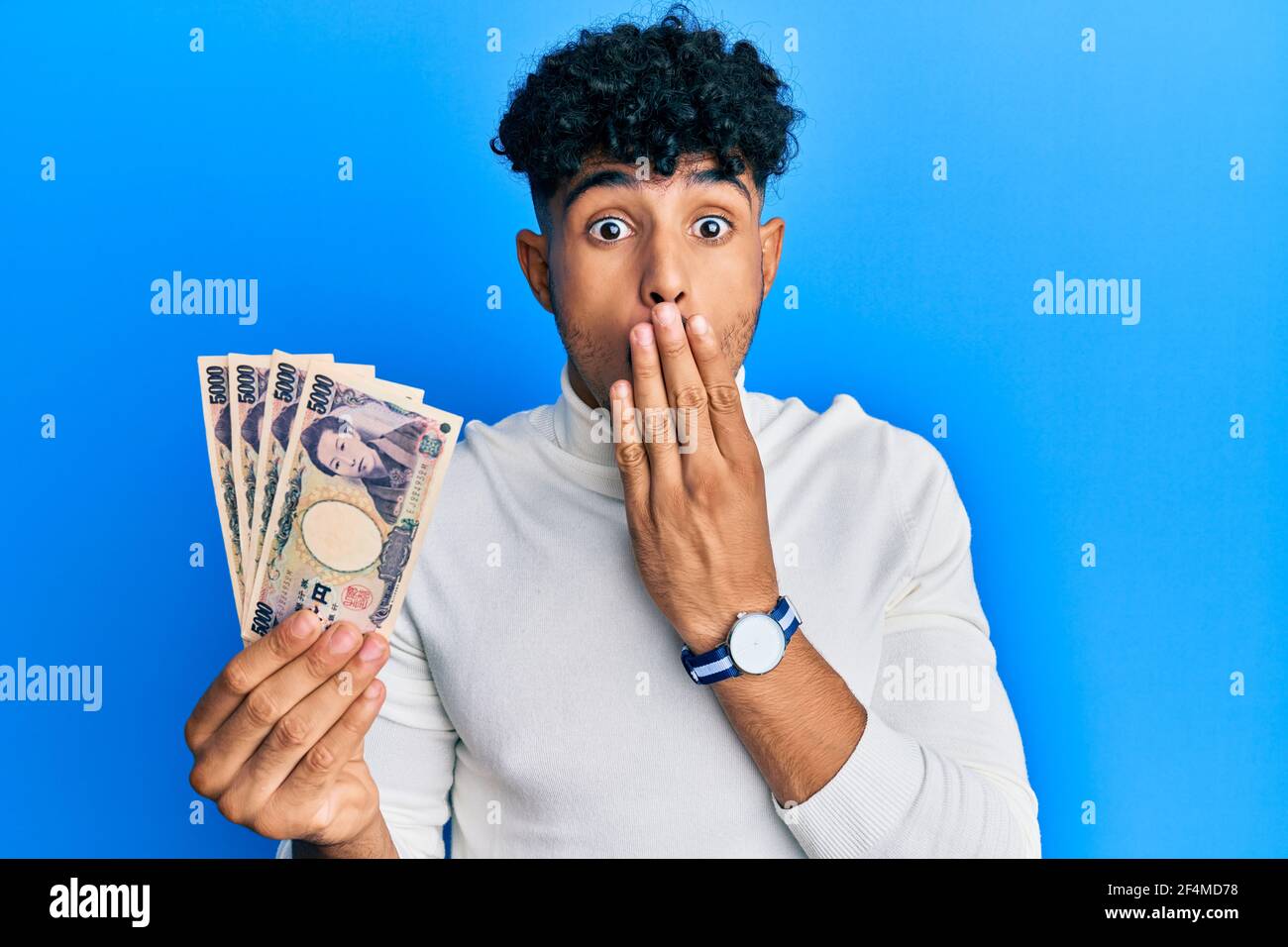 Young arab handsome man holding 5000 japanese yen banknotes covering ...