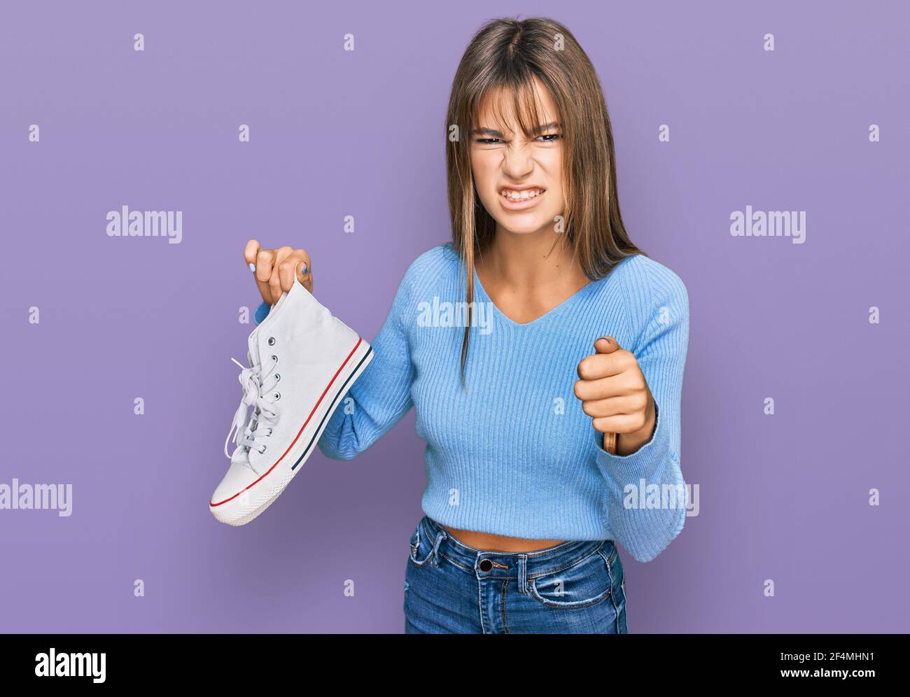 Teenager caucasian girl taking casual white shoes from box annoyed and frustrated shouting with anger, yelling crazy with anger and hand raised Stock Photo