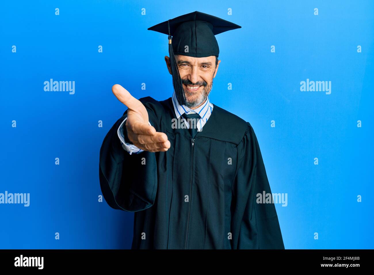 Middle age hispanic man wearing graduation cap and ceremony robe ...