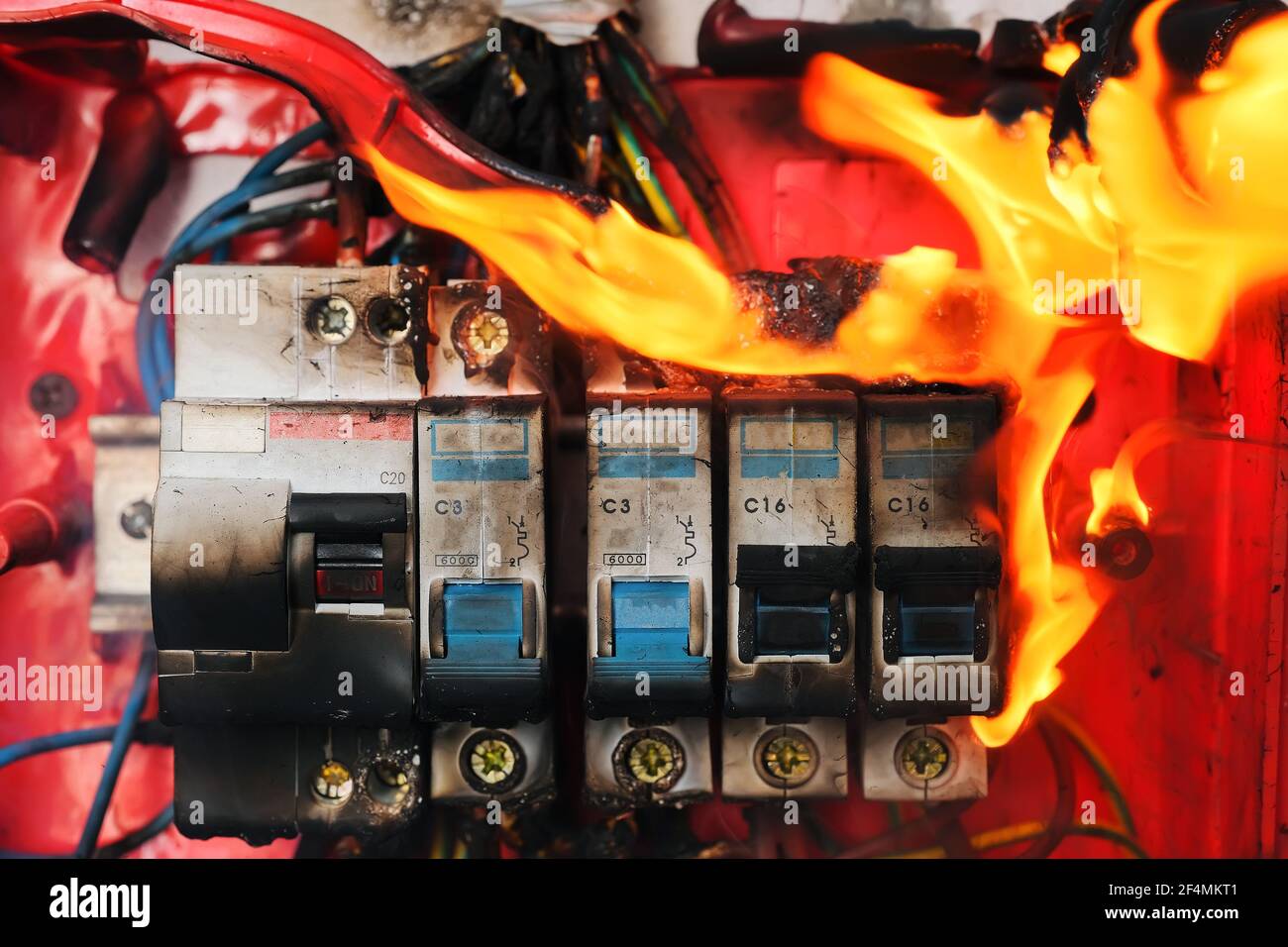 Burning switchboard from overload or short circuit on wall closeup Stock Photo