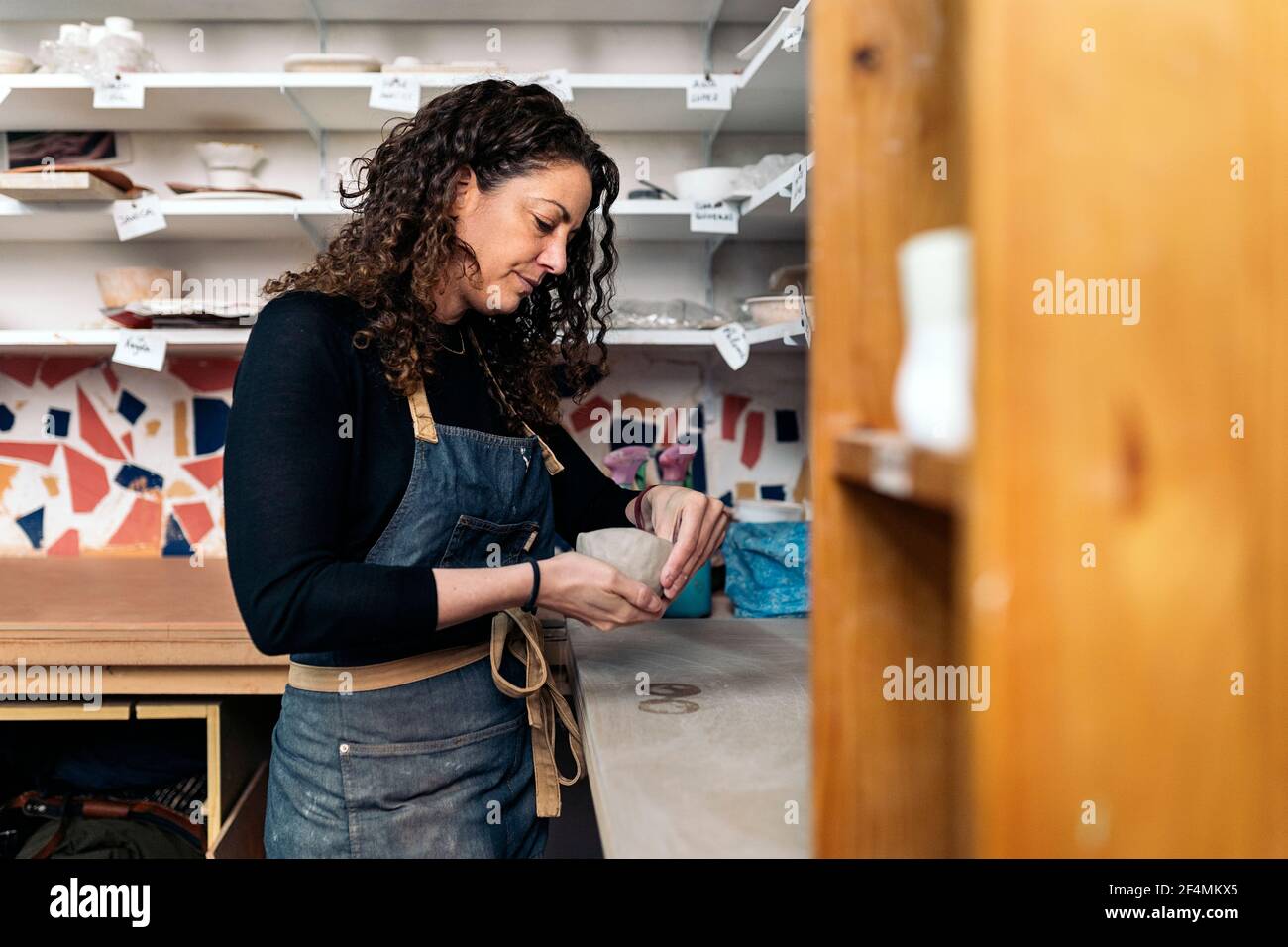 Stock photo of focused woman shaping clay during her pottery class. Stock Photo
