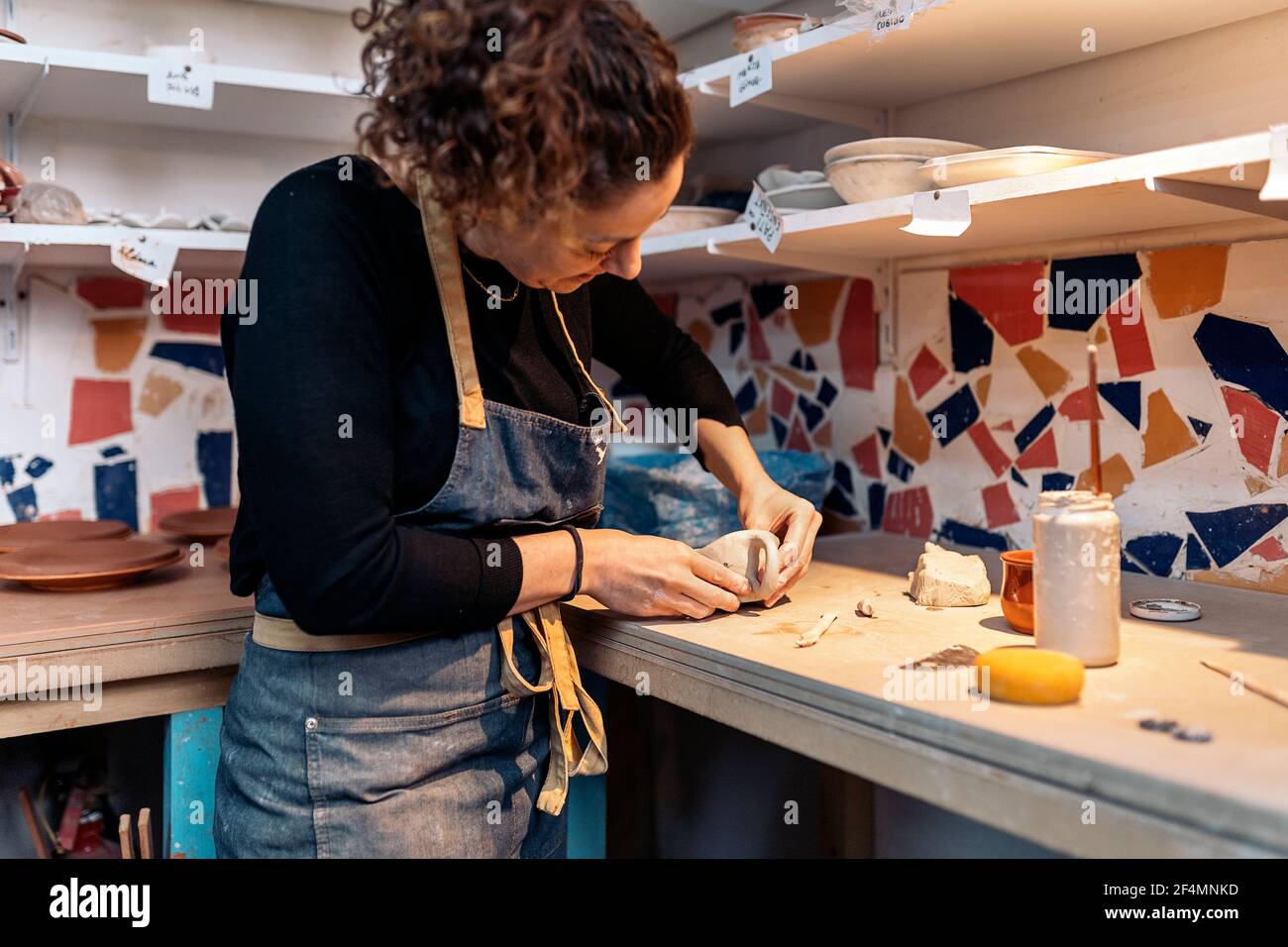 Stock photo of concentrated woman in apron working in pottery atelier ...