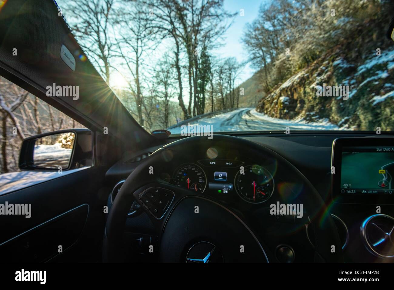 POV on a Mercedes-Benz A-class car interior with the sun facing, on a snowy winter road. Luxurious and cosy Dashboard and finition. Stock Photo