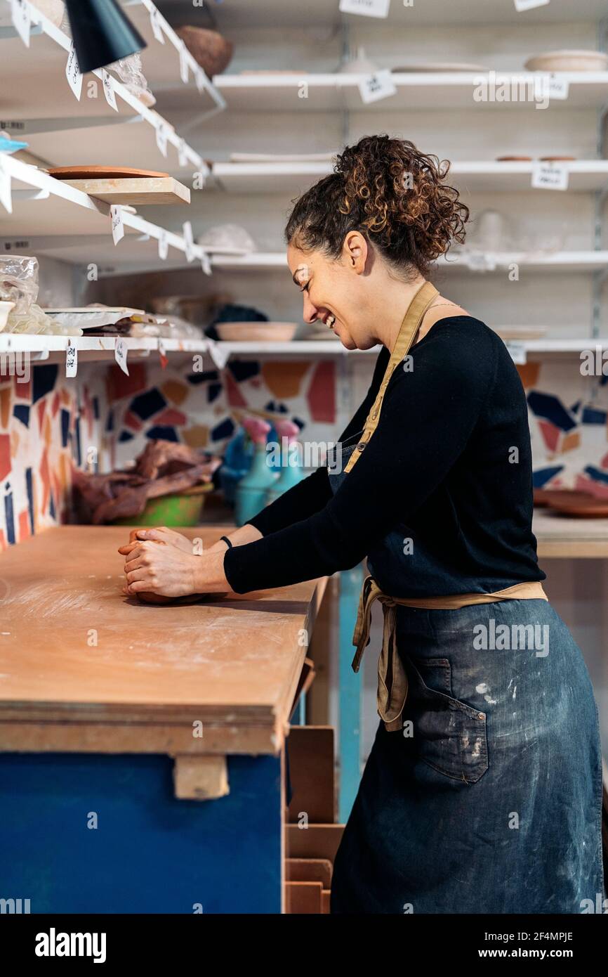 Stock photo of happy woman wearing apron shaping clay in pottery class ...