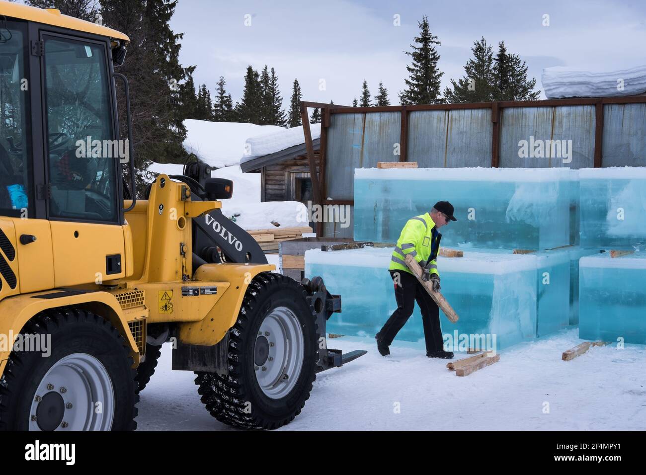 Man stacks rectangular cut ice block from a frozen lake needed to build