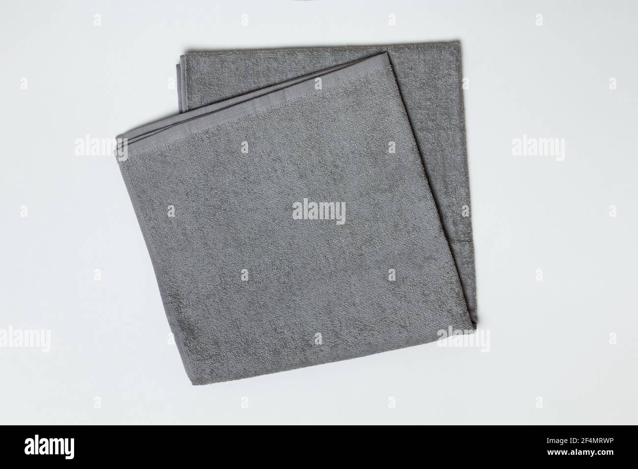 Gray folded towel on a white background. Close-up flat lay top view. Stock Photo