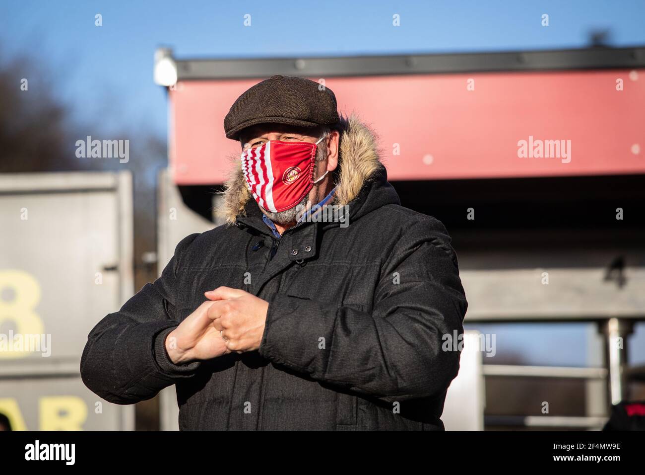 Male football supporter enters stadium and sanitises hands whilst wearing face covering during coronavirus, Covid-19 pandemic in England, UK Stock Photo