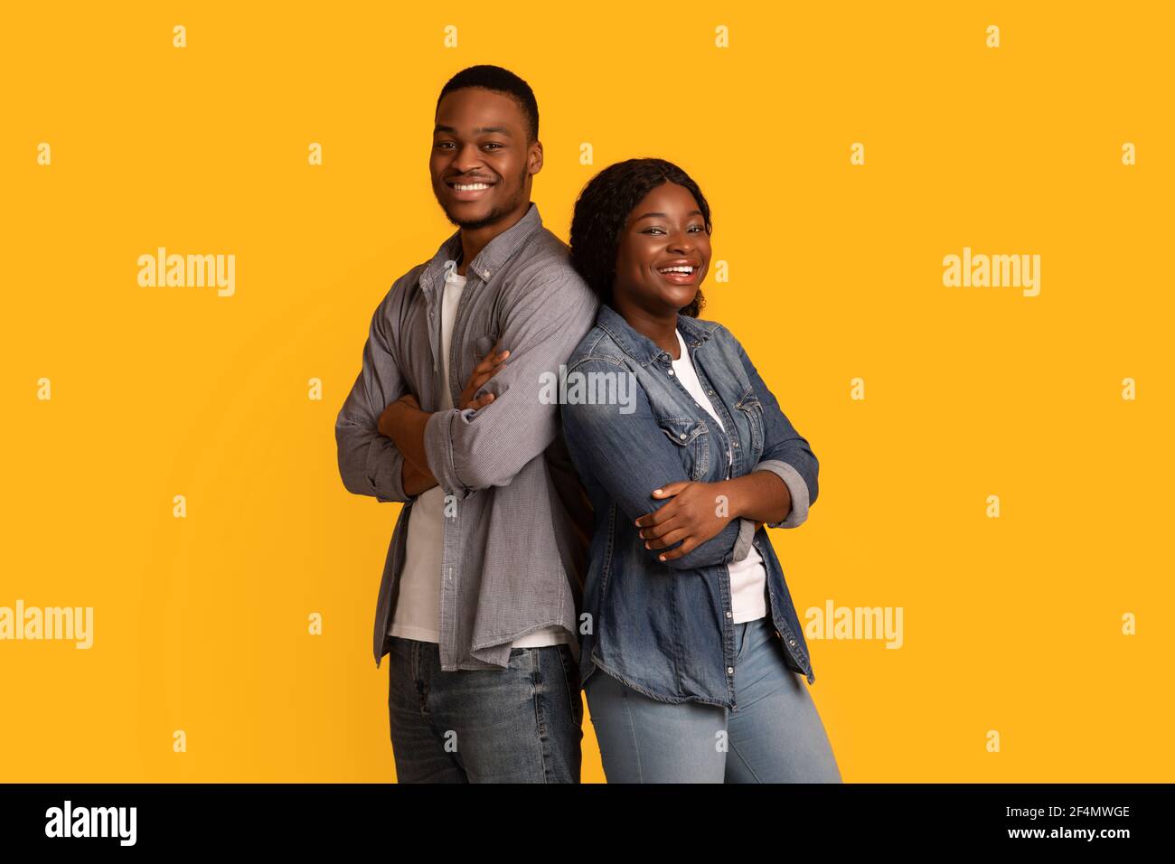 Happy black man and woman standing back to back with folded arms Stock ...