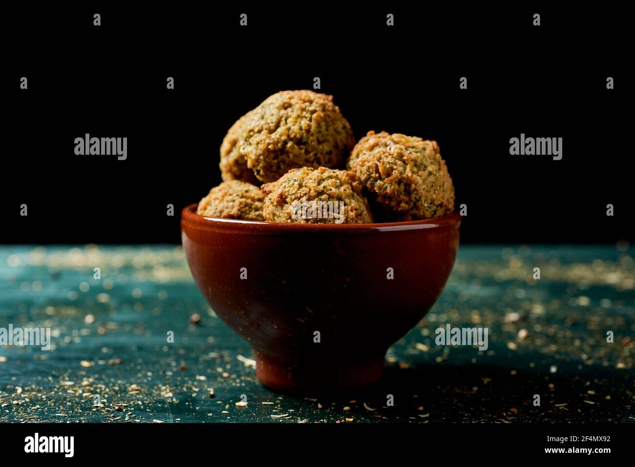 closeup of an earthenware bowl with some falafel on a rustic green wooden table Stock Photo