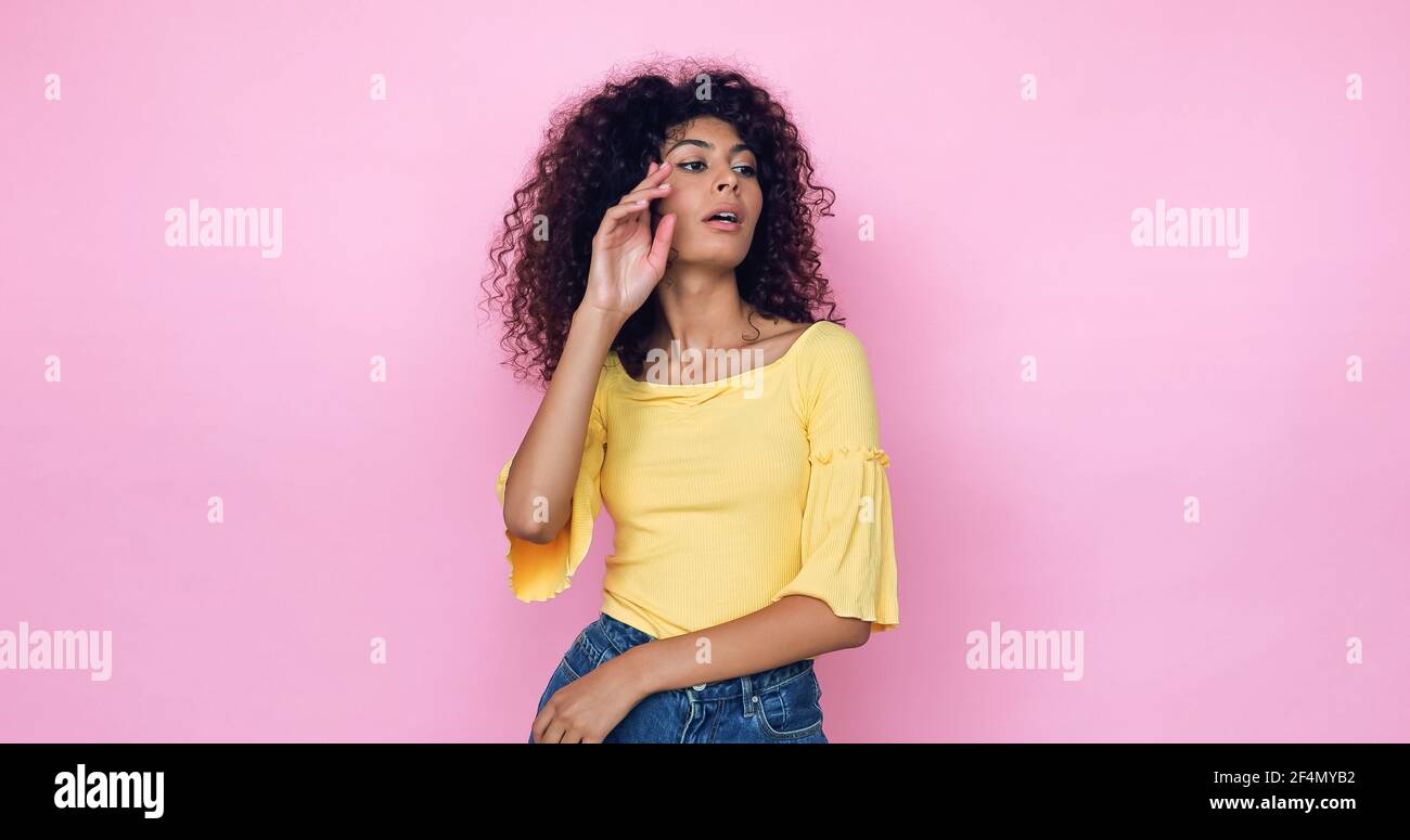 curly young model posing and looking away isolated on pink Stock Photo