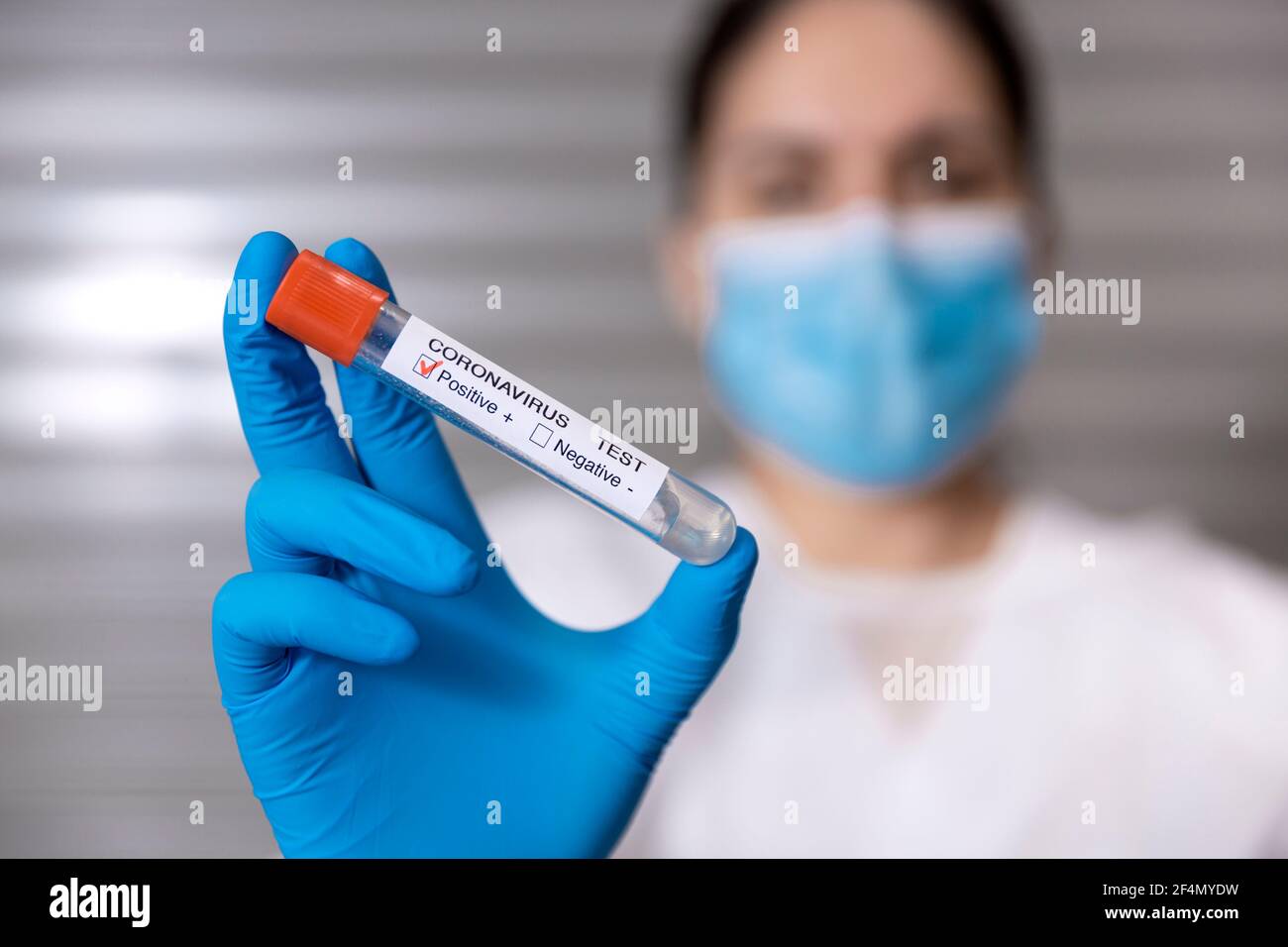 Close up of healthcare worker showing a test tube with a positive sample of Covid-19 virus. Selective focus, space for text. Stock Photo