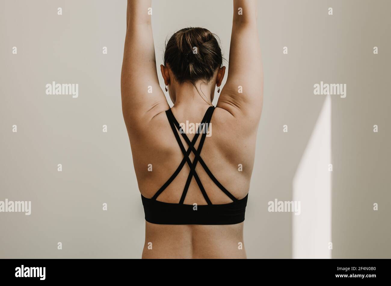 https://c8.alamy.com/comp/2F4N0B0/partial-upper-body-backside-portrait-of-a-woman-in-a-strappy-yoga-top-with-arms-raised-back-muscles-engaged-with-a-white-background-2F4N0B0.jpg