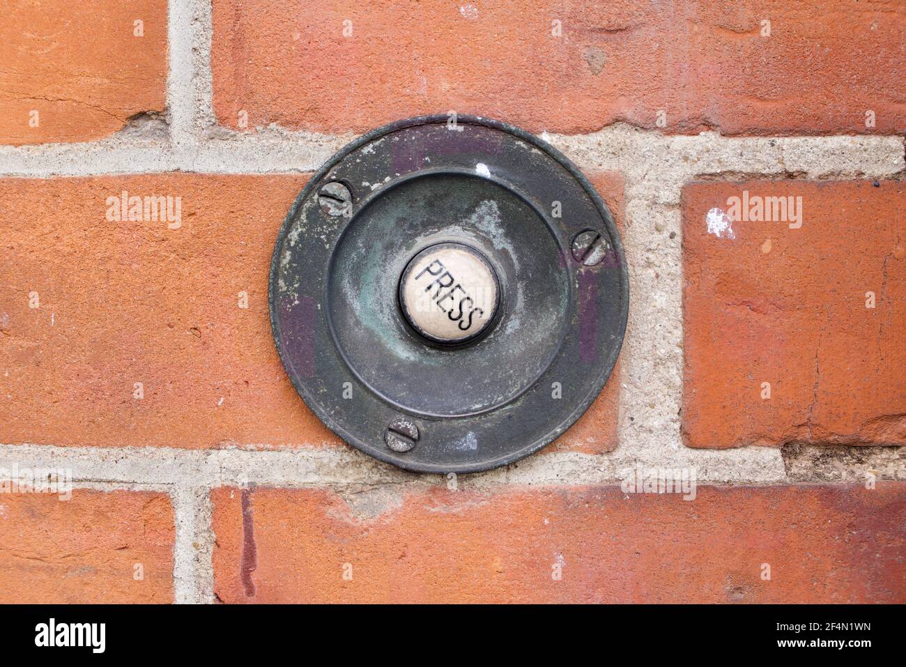 Old fashioned door bell in brickwork with the word Press  Stock Photo