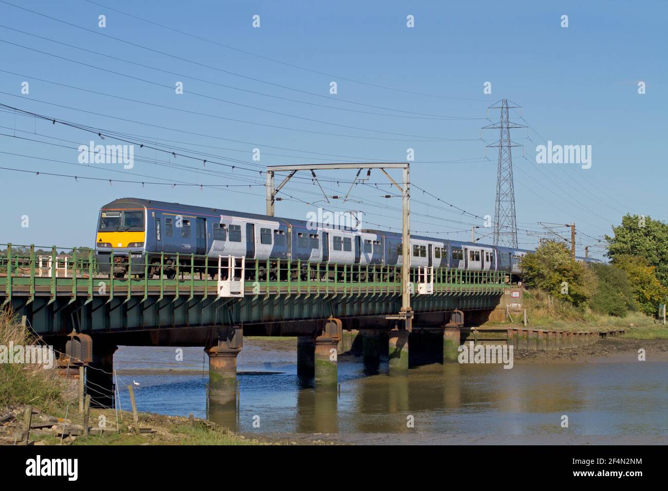 A Class 321 electrical multiple unit number 321318 working a National Express Anglia service crossing the River Stour at Manningtree. Stock Photo