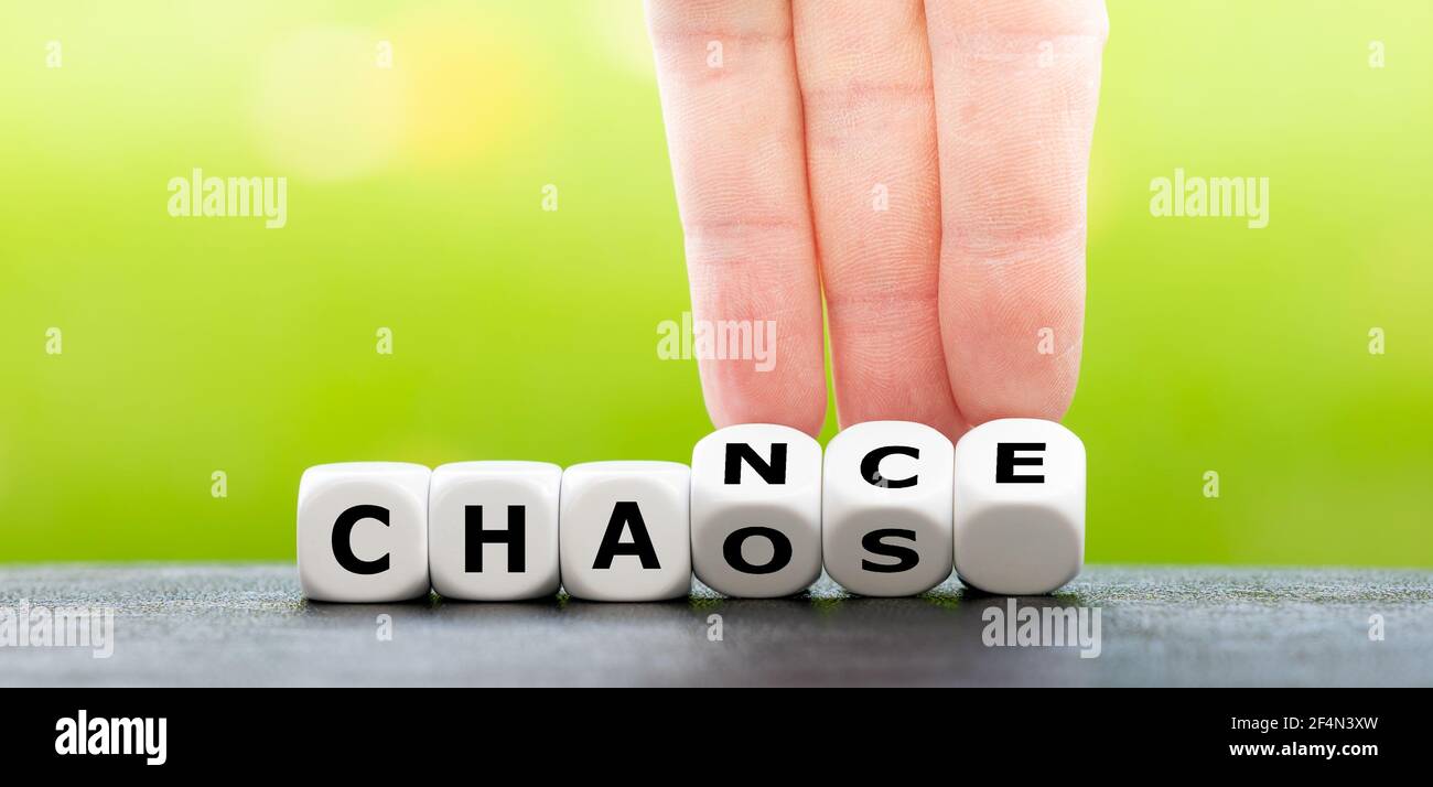 Hand turns dice and changes the word chaos to chance. Stock Photo