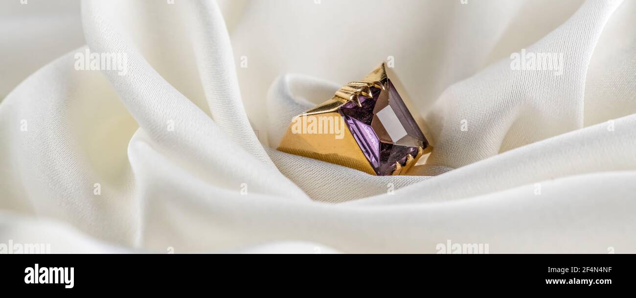 Gold ring with alexandrite on white color royalty silk fabric satin