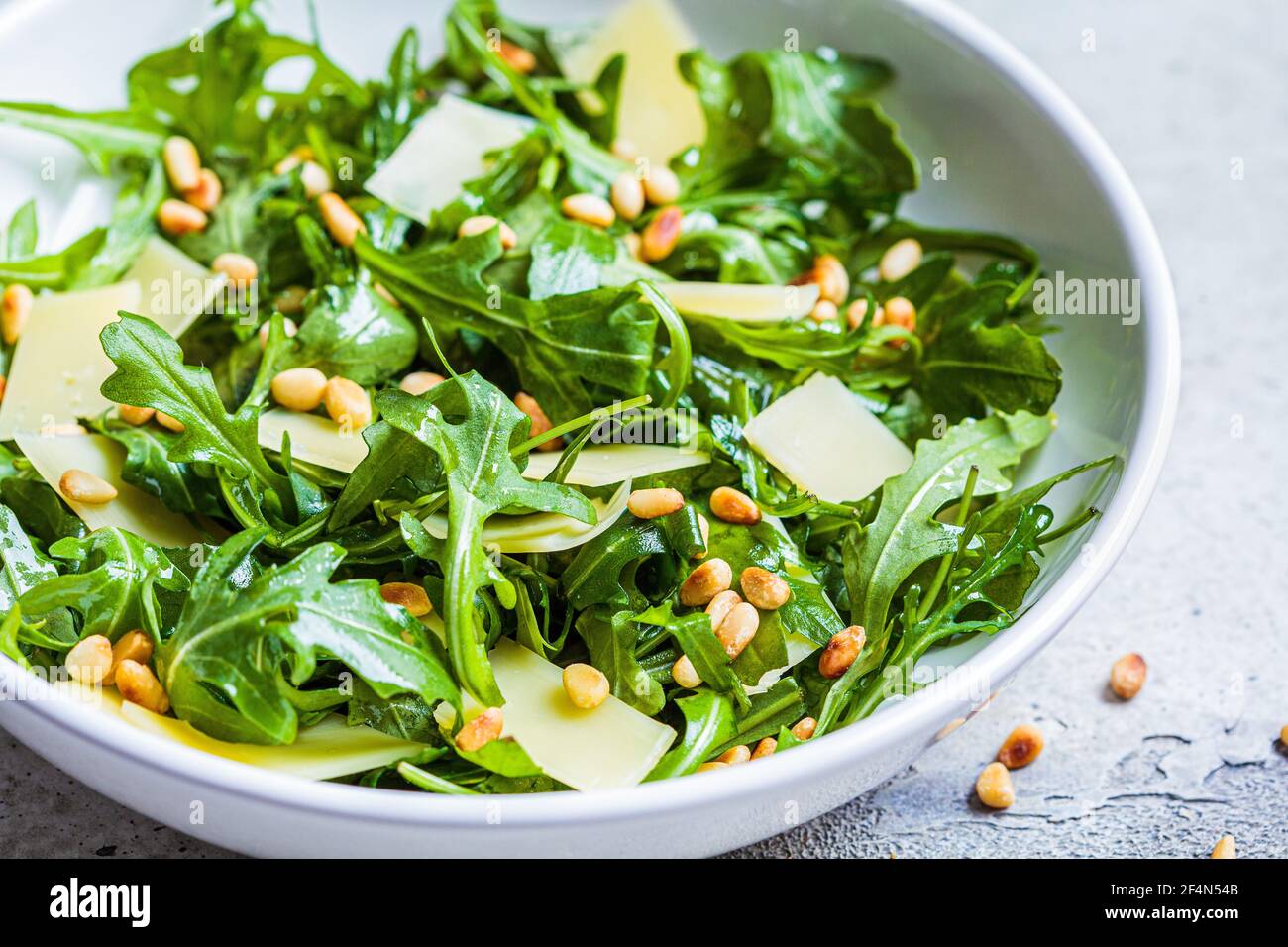 Arugula and parmesan salad with pine nuts in a white bowl. Italian
