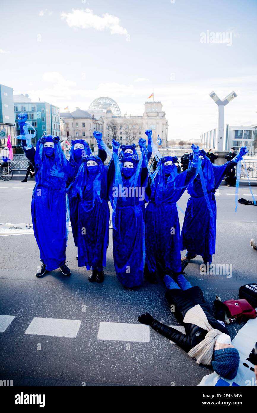 Berlin, Germany. 22nd Mar, 2021. 'Blue Rebels' raise their fists during a so-called 'die-in' performance of the environmental protection movement 'Extinction Rebellion' on the occasion of World Water Day with the motto 'Protect water - stop fracking worldwide' on the Marschall Bridge in front of the Reichstag building. Credit: Christoph Soeder/dpa/Alamy Live News Stock Photo