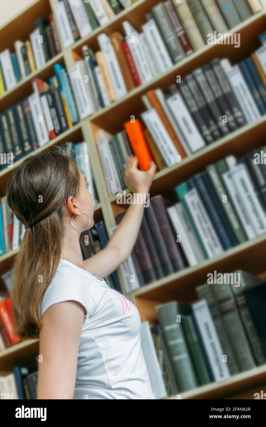Back to school library concept. Student girl holding book on her head ...
